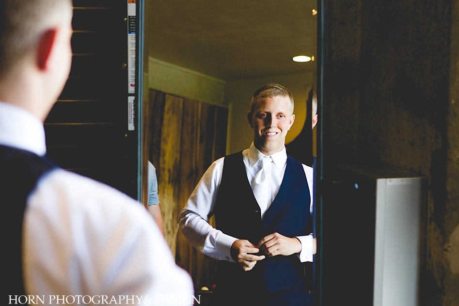 Groom looking in mirror at Horn Photography and Design Wedding Photographer