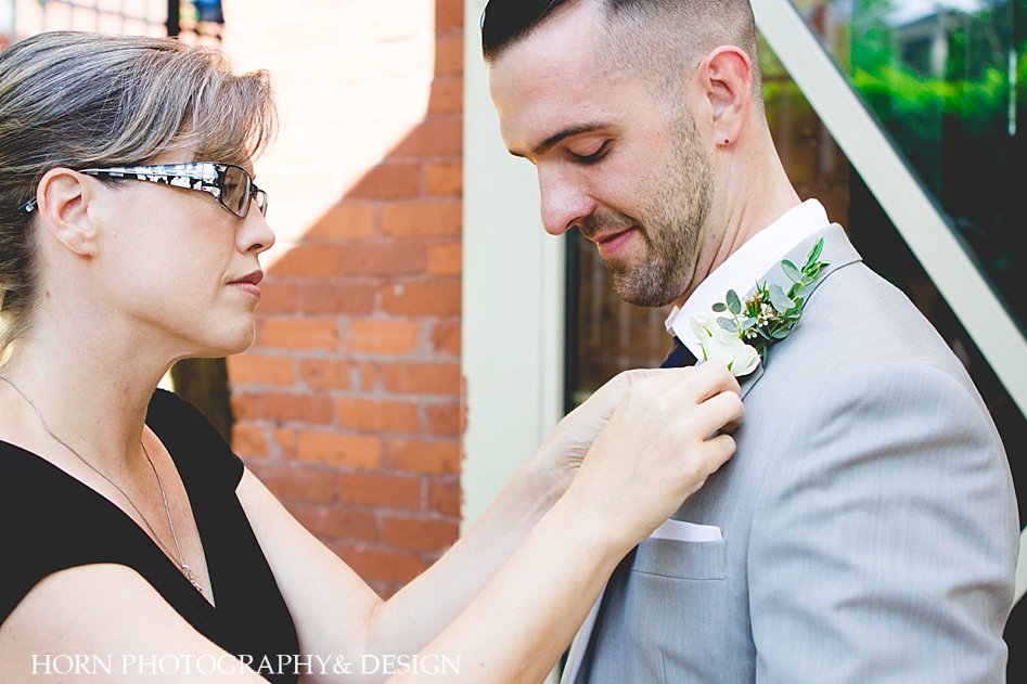 Mother pins boutonnière on groom