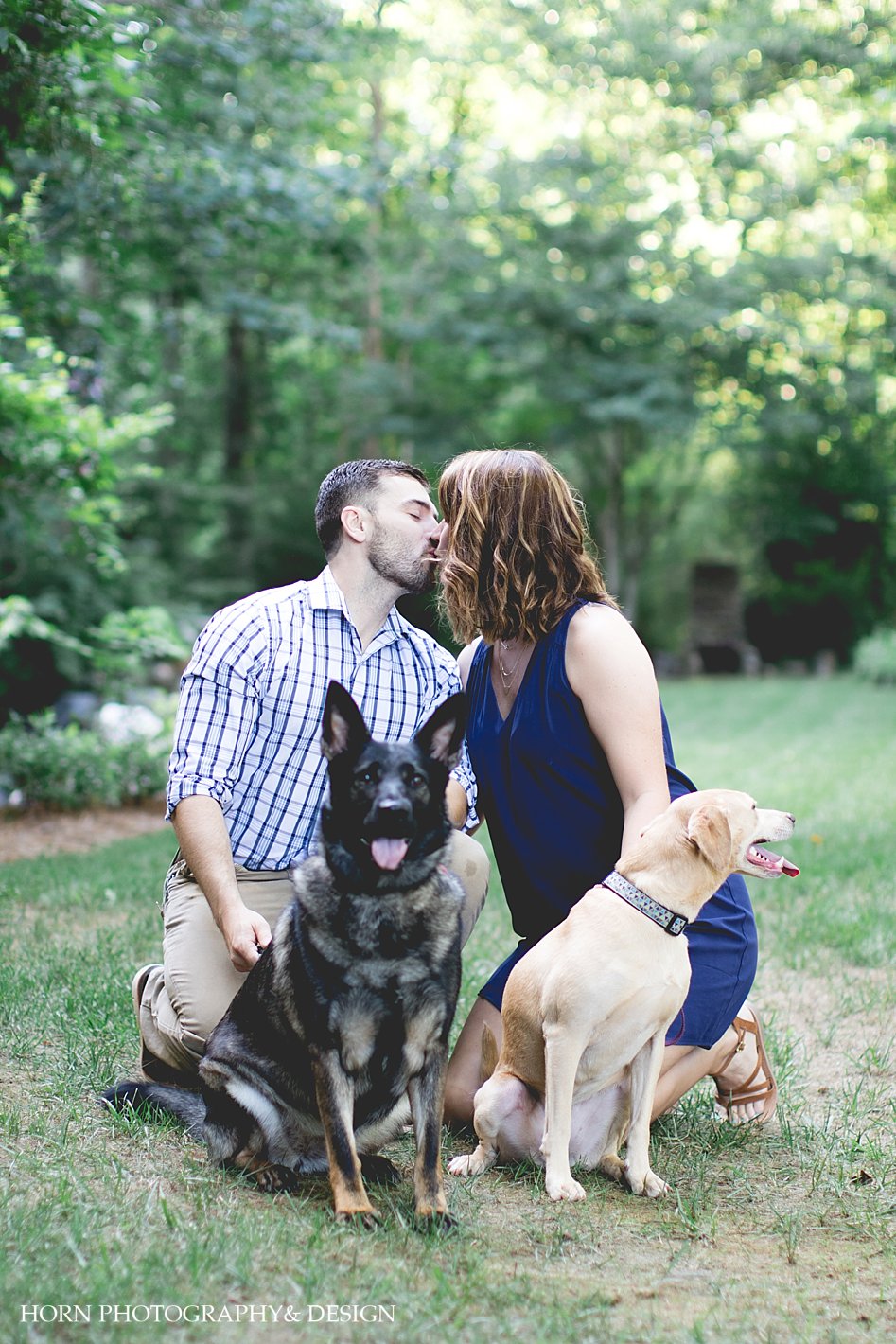engaged couple kiss while dogs face camera