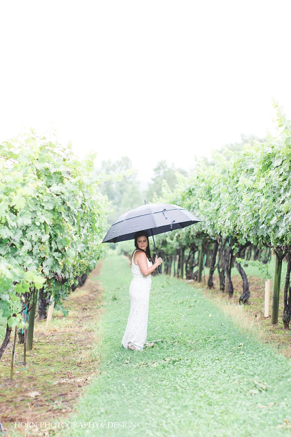 Bride in Vineyard during rain with umbrella