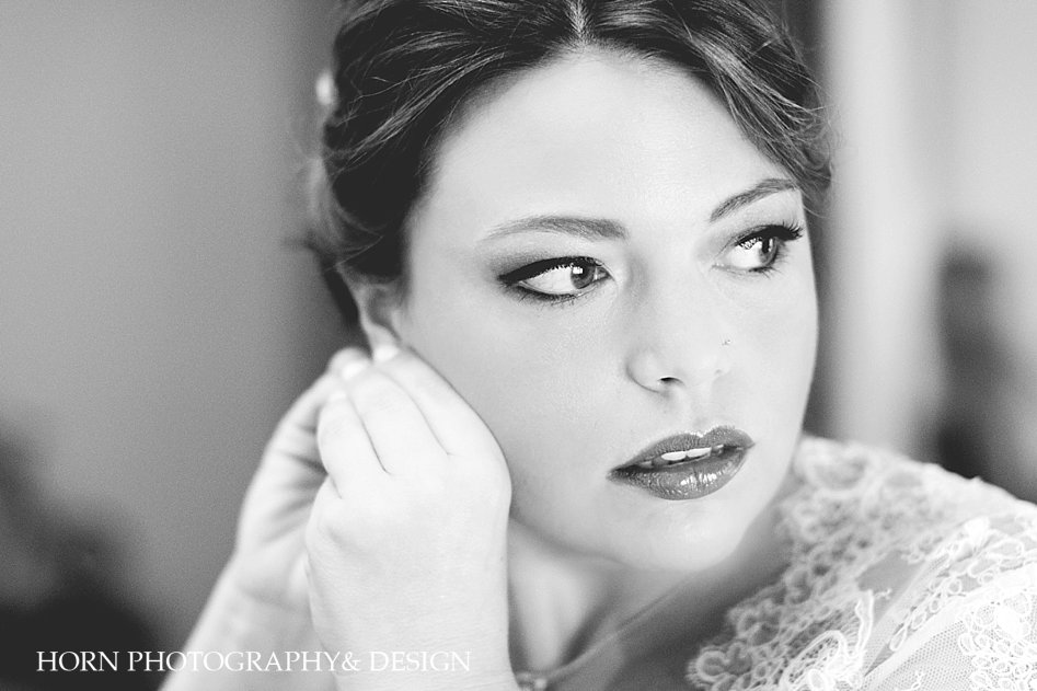 Beautiful bride putting on her earrings in black and white
