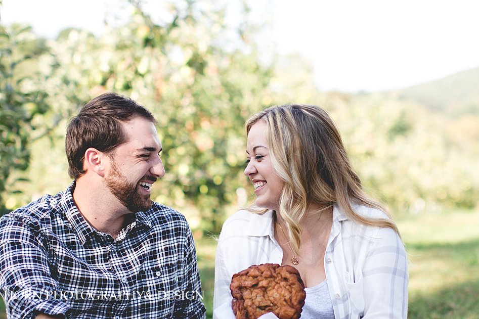 engaged couple shares an apple fritter, Engagement shoot Horn photography and Design Husband and Wife Photographer Team