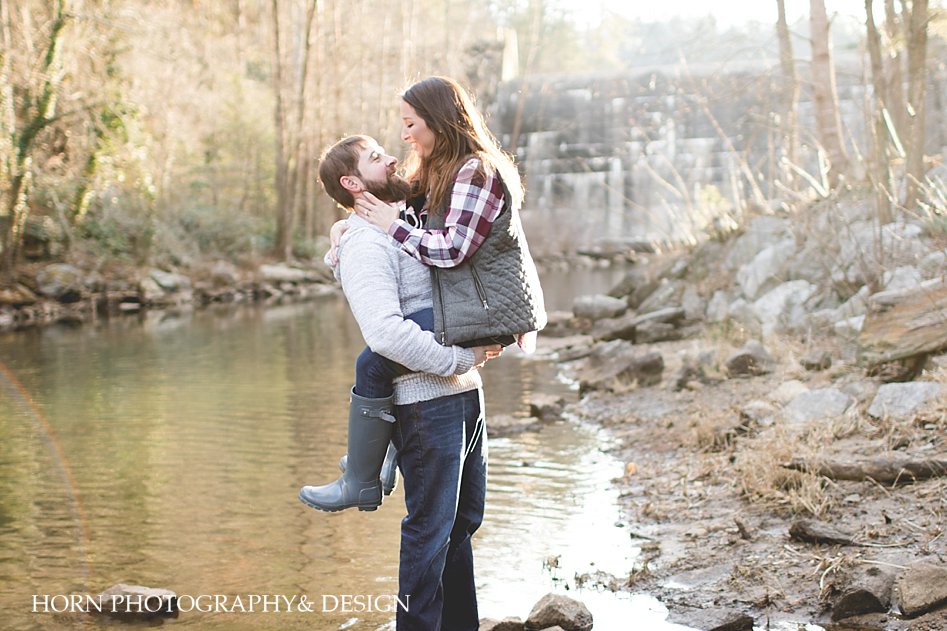 guy lifts girl by river side horn photography and design Adventurous Engagement 