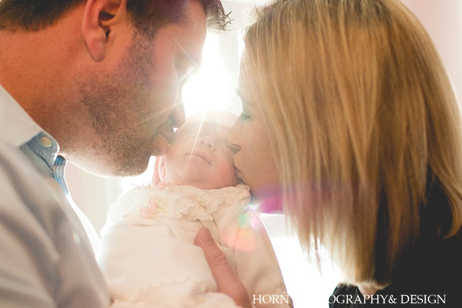 natural light Newborn Lifestyle Shoot mother and father kiss baby