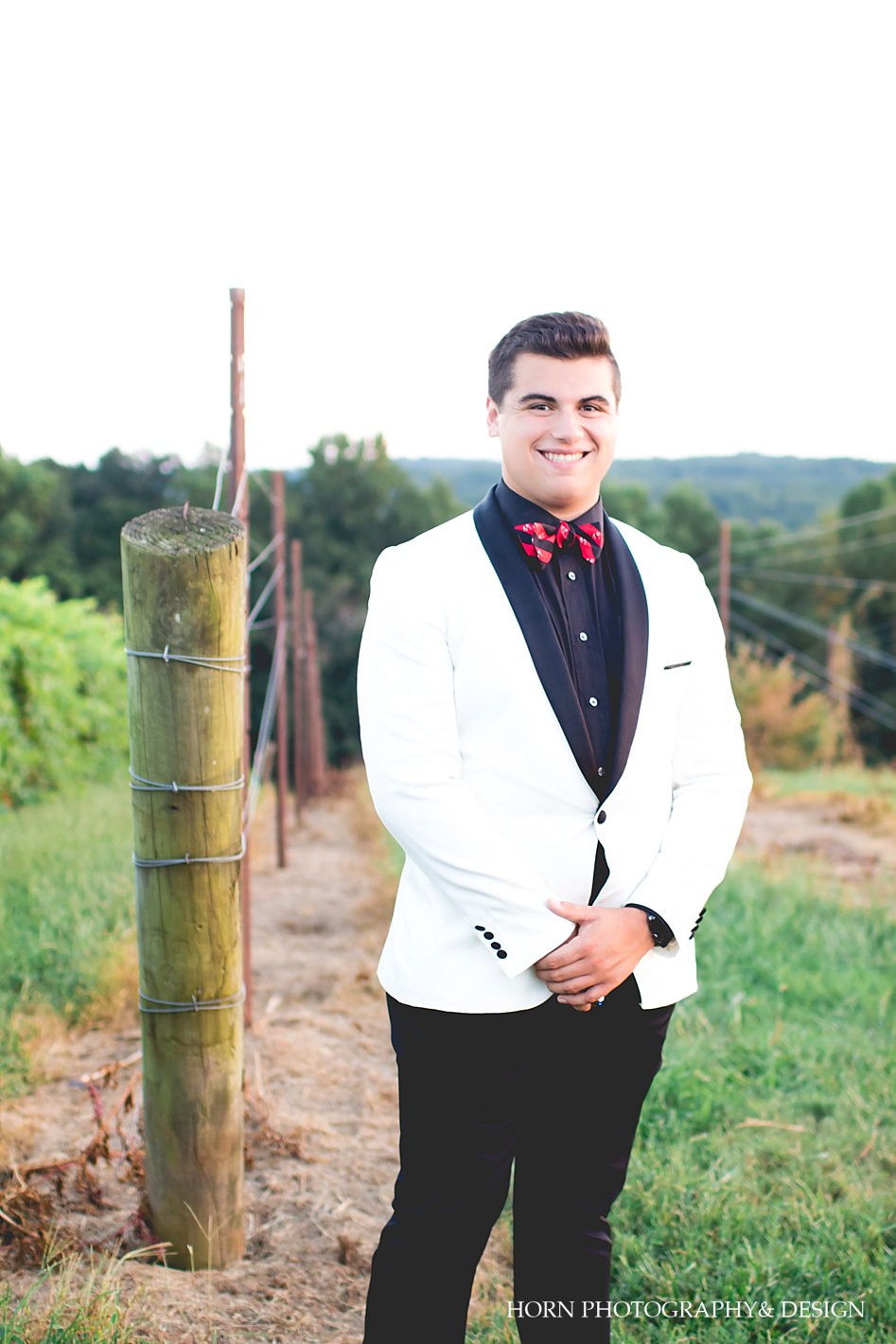 senior student in white tux jacket with UGA bowtie at a vineyard