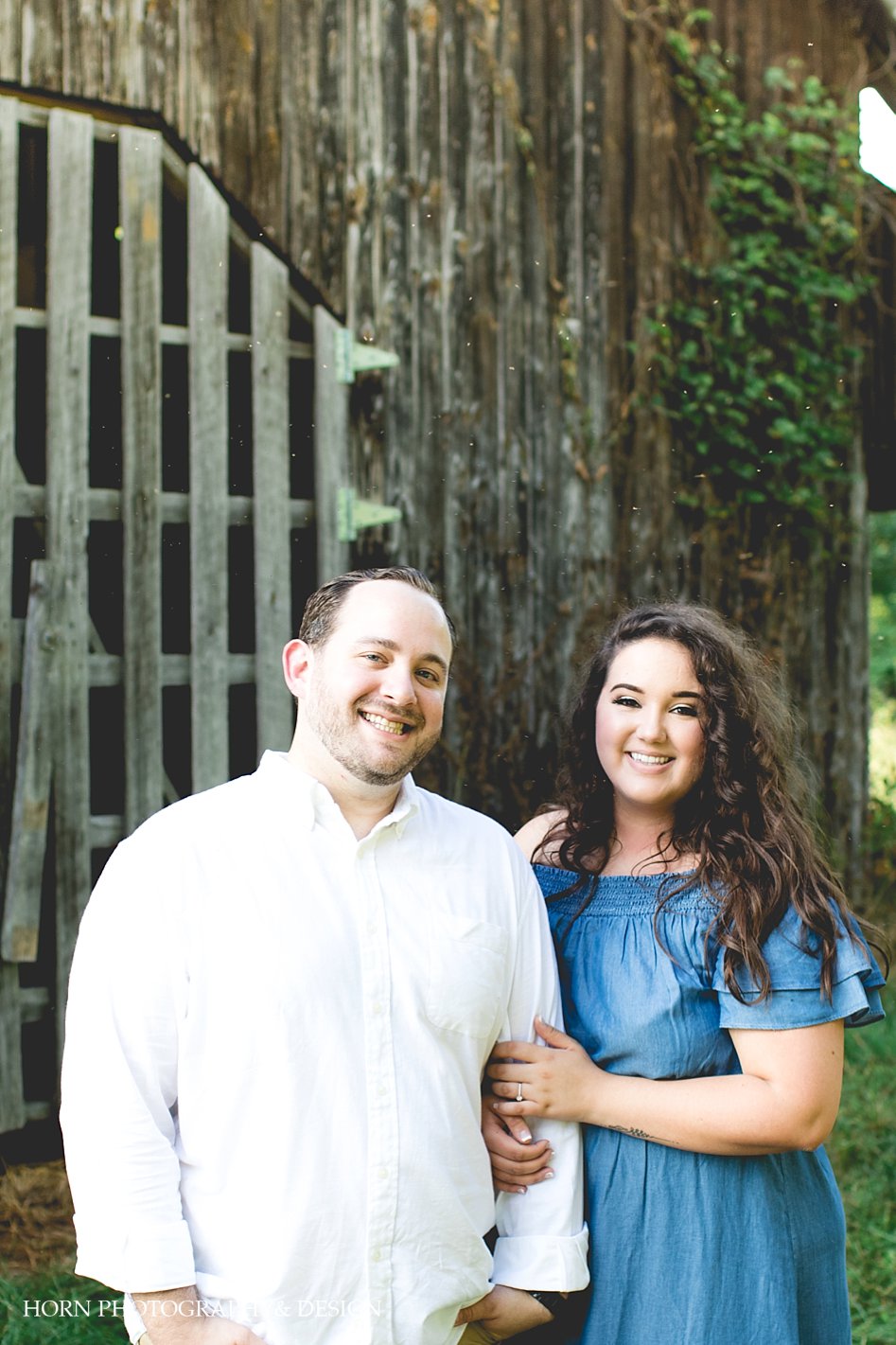 happy engaged couple in front of barn