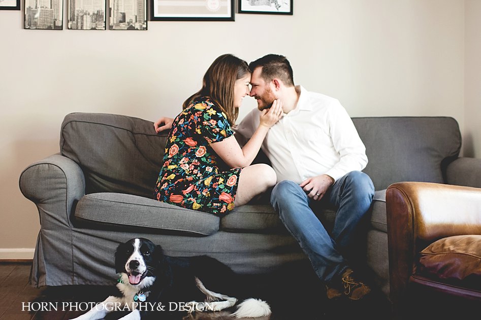 husband and wife cuddle on couch with dog