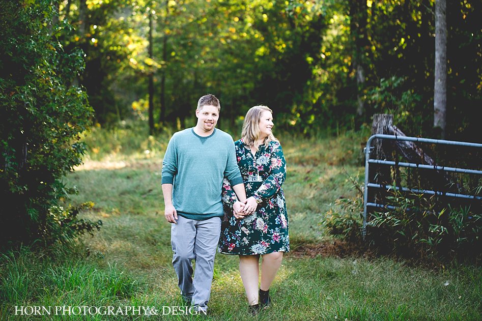 engaged couple walks through gate in green floral dress