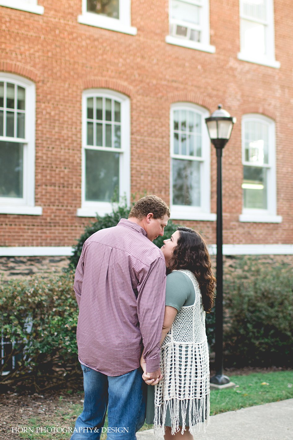 couple stands in front of building holding hands Anniversary Session Downtown Dahlonega