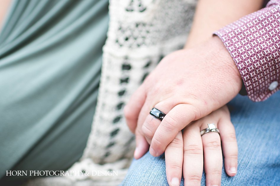 husband and wife team Anniversary Session Downtown Dahlonega holding hands with wedding bands