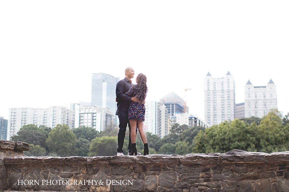 atlanta skyline with couple standing on wall at Piedmont park two year anniversary