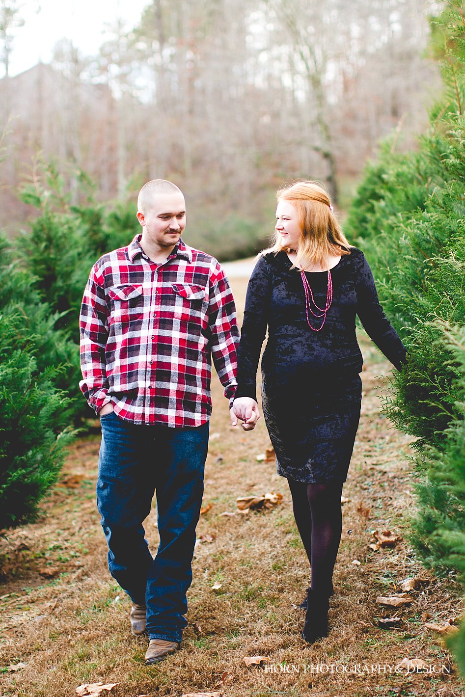 maternity session couple walking through evergreens