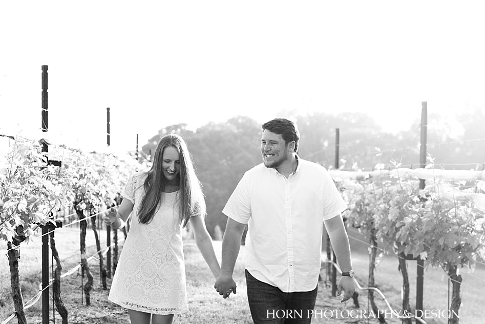 engaged couple walking holding hands in vineyard dahlonega