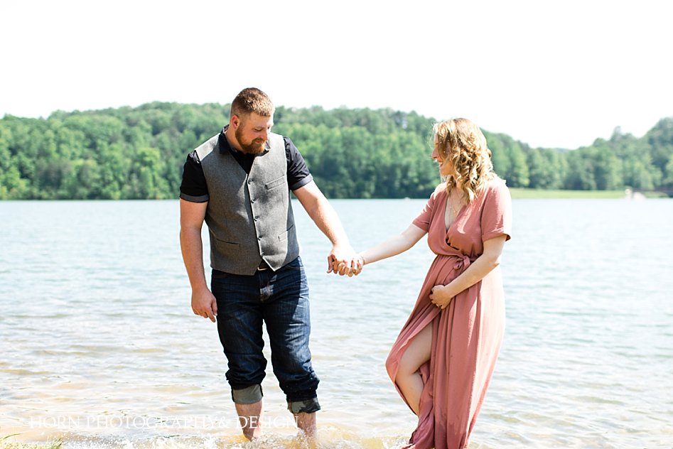 dad holding hands in lake playful maternity session horn photography and design husband wife team photo video photographers