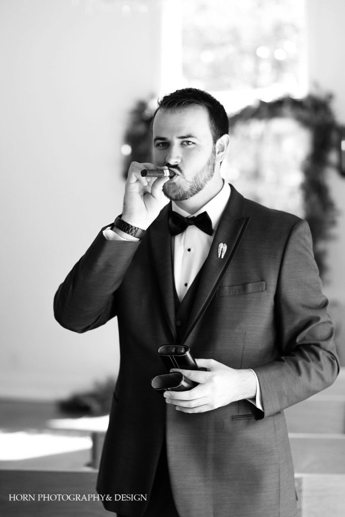 black and white groom smoking cigar getting ready