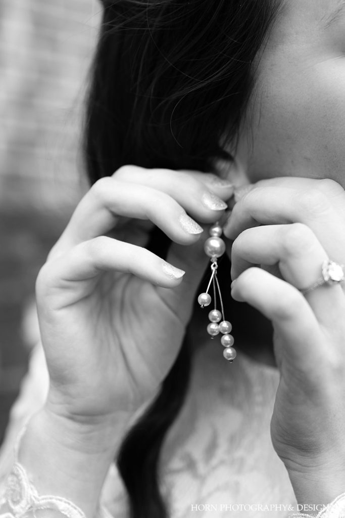 bride putting on pearl earrings black and white