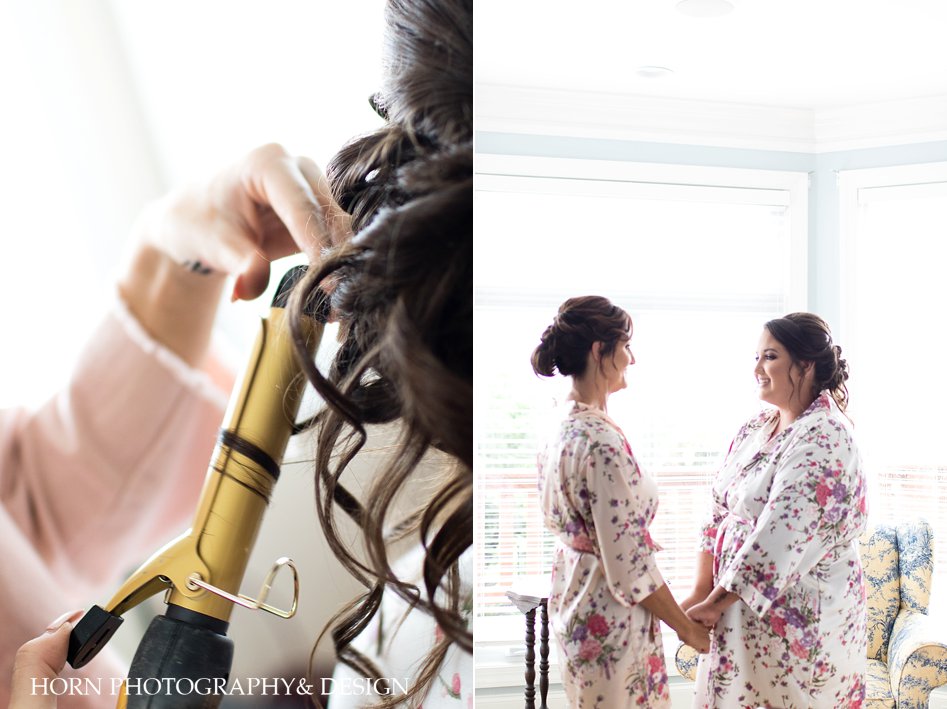 June summer wedding bride getting hair done next to bride holding hands with mother matching silk floral robe horn photography and design bright vibrant dreamy photography
