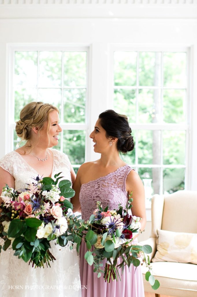 bride and bridesmaid candid pose eclectic floral bouquet lilac lace one shoulder bridesmaid dress Southern Charm horn photography and design