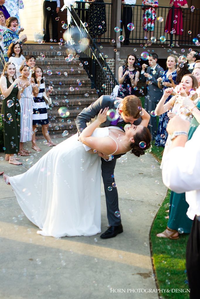 groom dipping and kissing bride in bubble parade leaving reception the beginning of forever horn photography and design