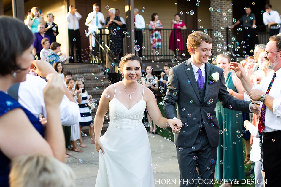 bride and groom leaving wedding reception in bubble parade holding hands southern summer outdoor weddings atlanta georgia horn photography and design
