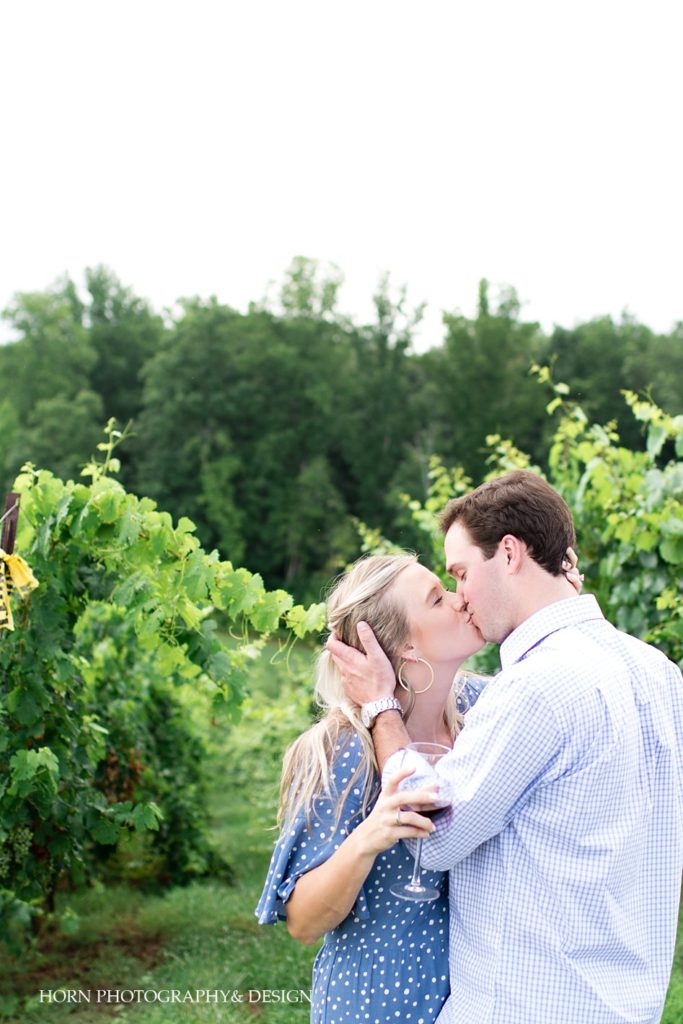 engagement photo kissing in vineyard with a glass of wine she said yes North Georgia horn photography and design