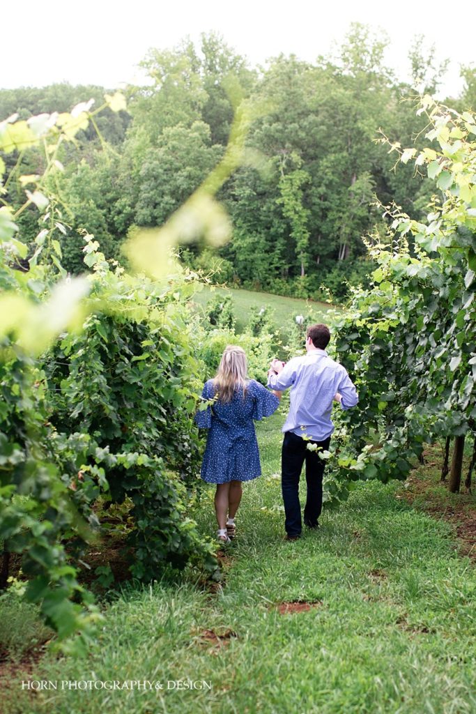 walking through the vineyard holding hands engagement photo session pose ideas North Georgia mountain vineyards horn photography and design