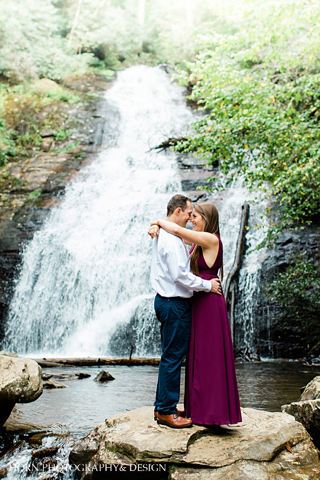 engaged couple embraces in front of waterfall north Georgia 