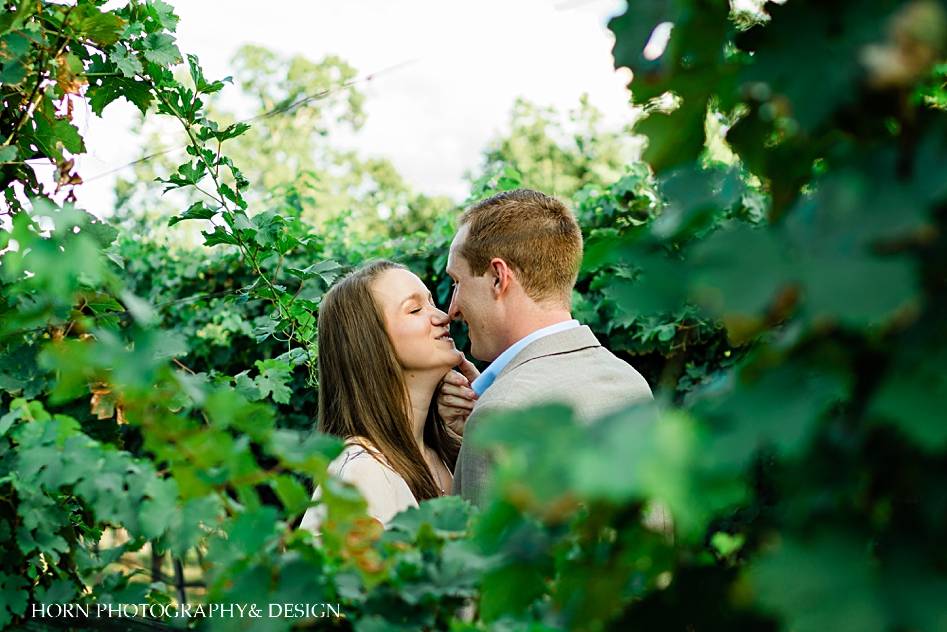 through the vines girl looks at camera guy looks at girl engagement shoot poses