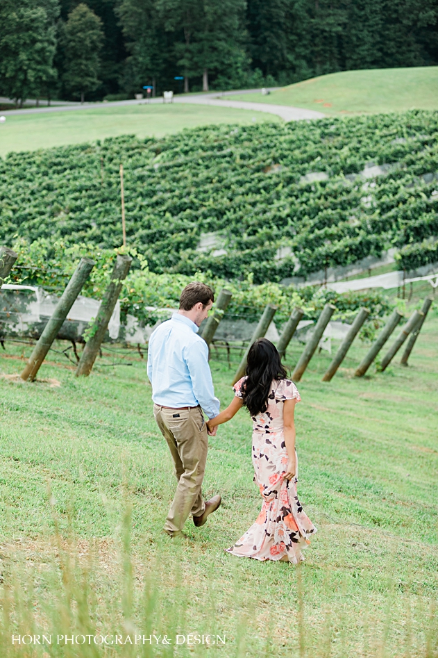 couple walks in vineyard Vineyard Engagement montaluce winery dahlonega Georgia engagement photography