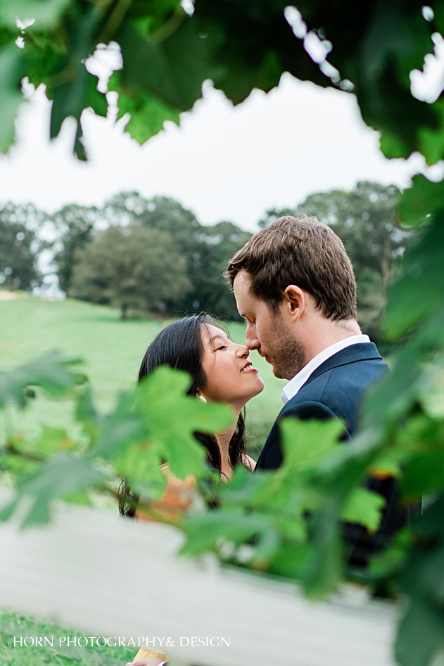 couple kisses in vines at North Georgia vineyard montaluce