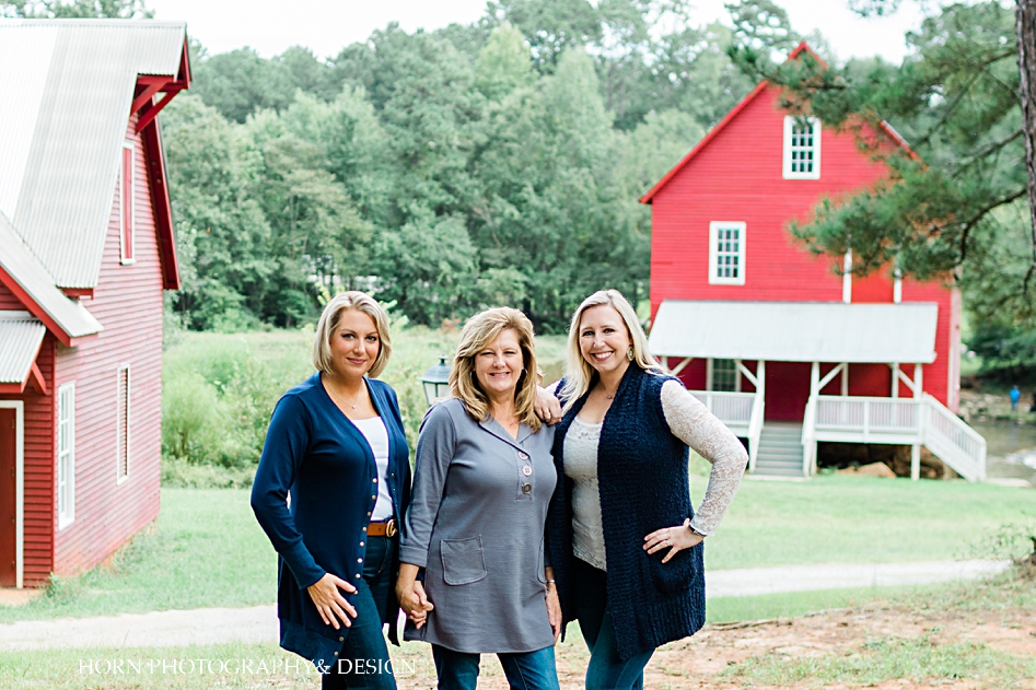 mother and daughters pose in front of red barn