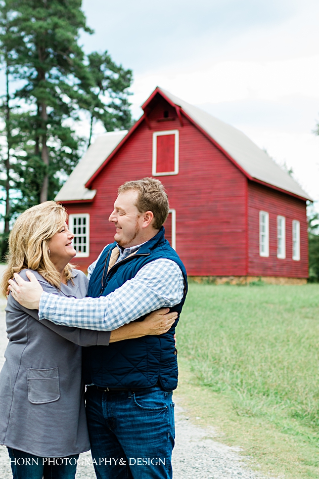 mother and son hug in front of red barn
