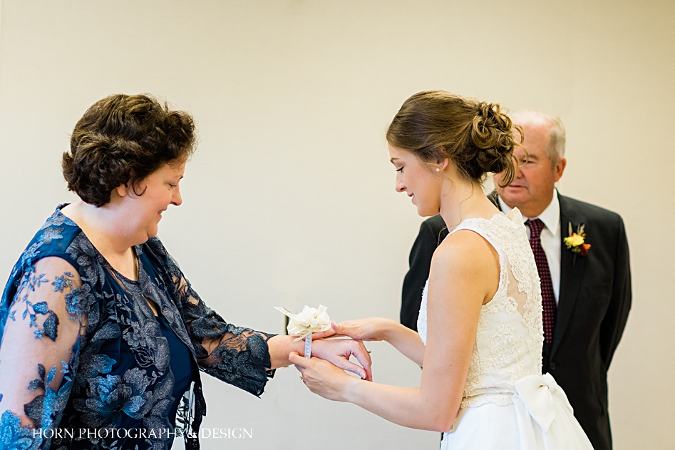 bride puts wrist corsage on mother of bride