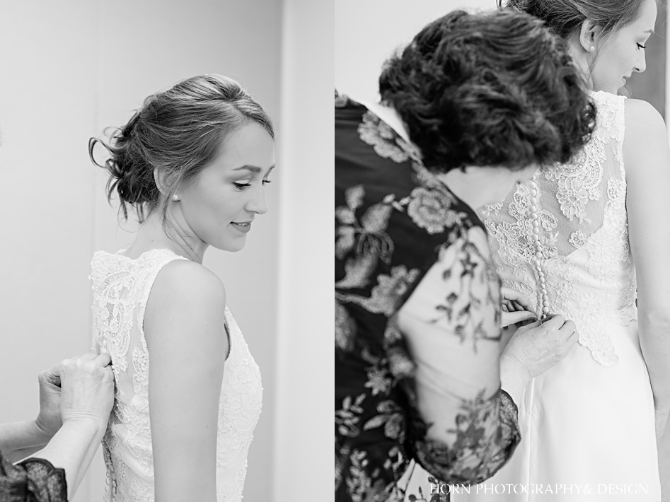 mother of bride buttoning up bride's wedding dress at catholic wedding black and white