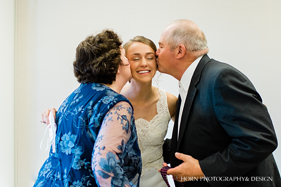 parents of bride kiss on cheeks